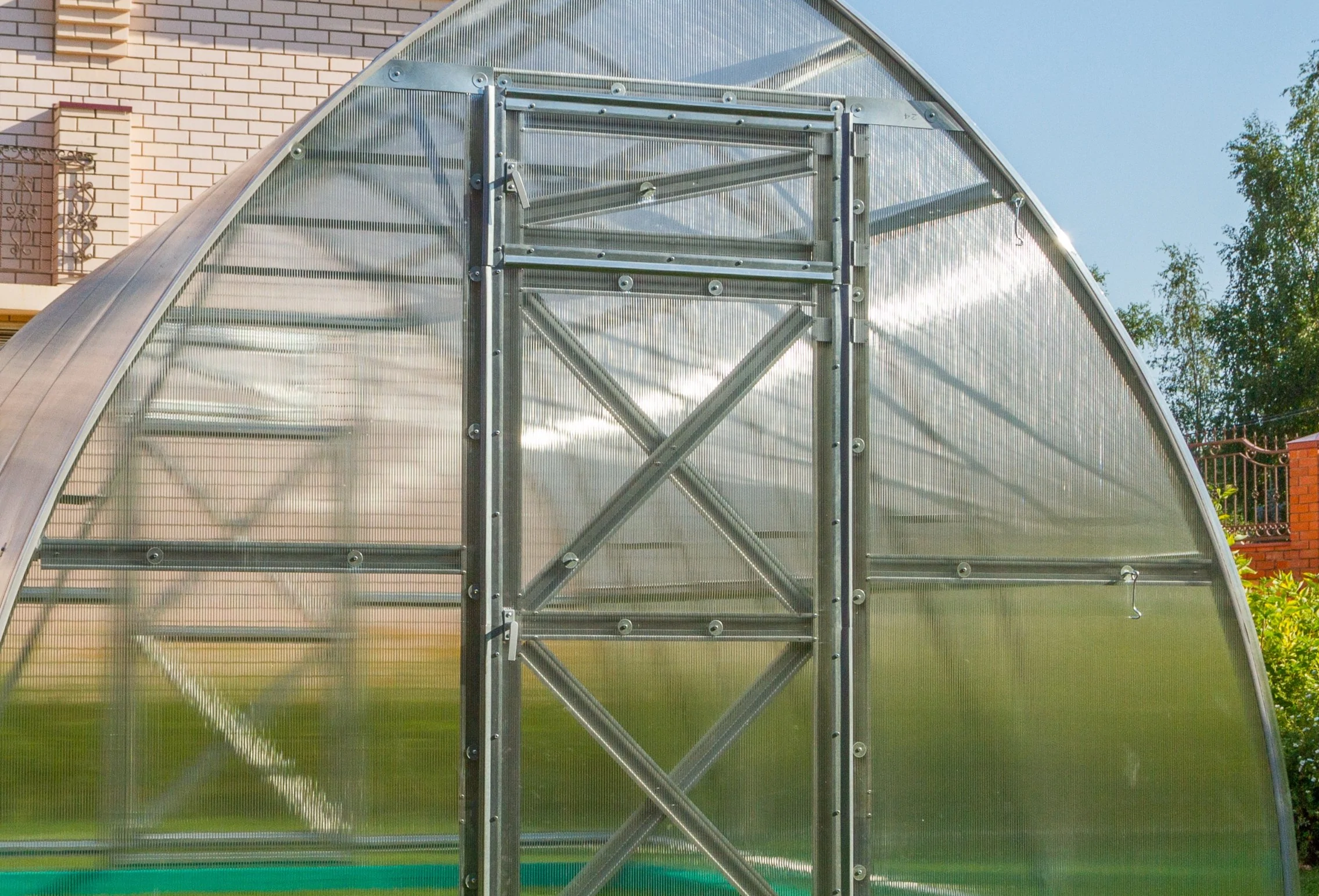 Polycarbonate hoop greenhouse door and metal frame