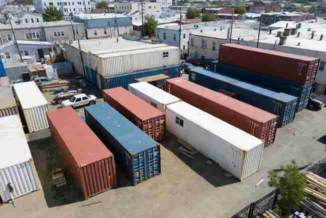 Multiple shipping containers ready for conversion into modular cannabis growing setups on an urban lot