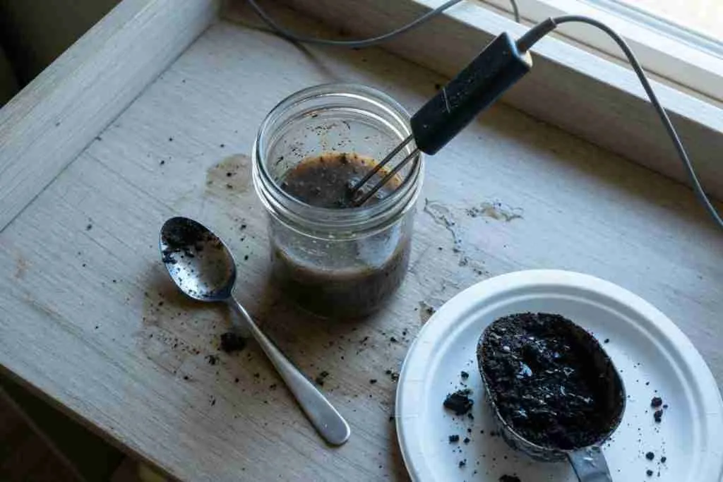 Soil slurry in a mason jar with a meter probe on a potting bench