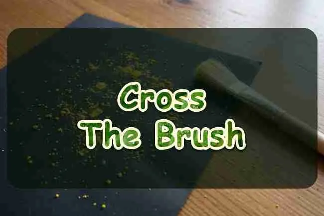 Yellow pollen on black paper beside a small brush